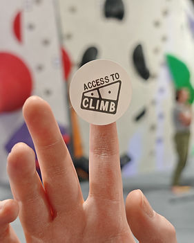 Finger balancing a sticker that says Access to Climb in and indoor rock climbing gym.