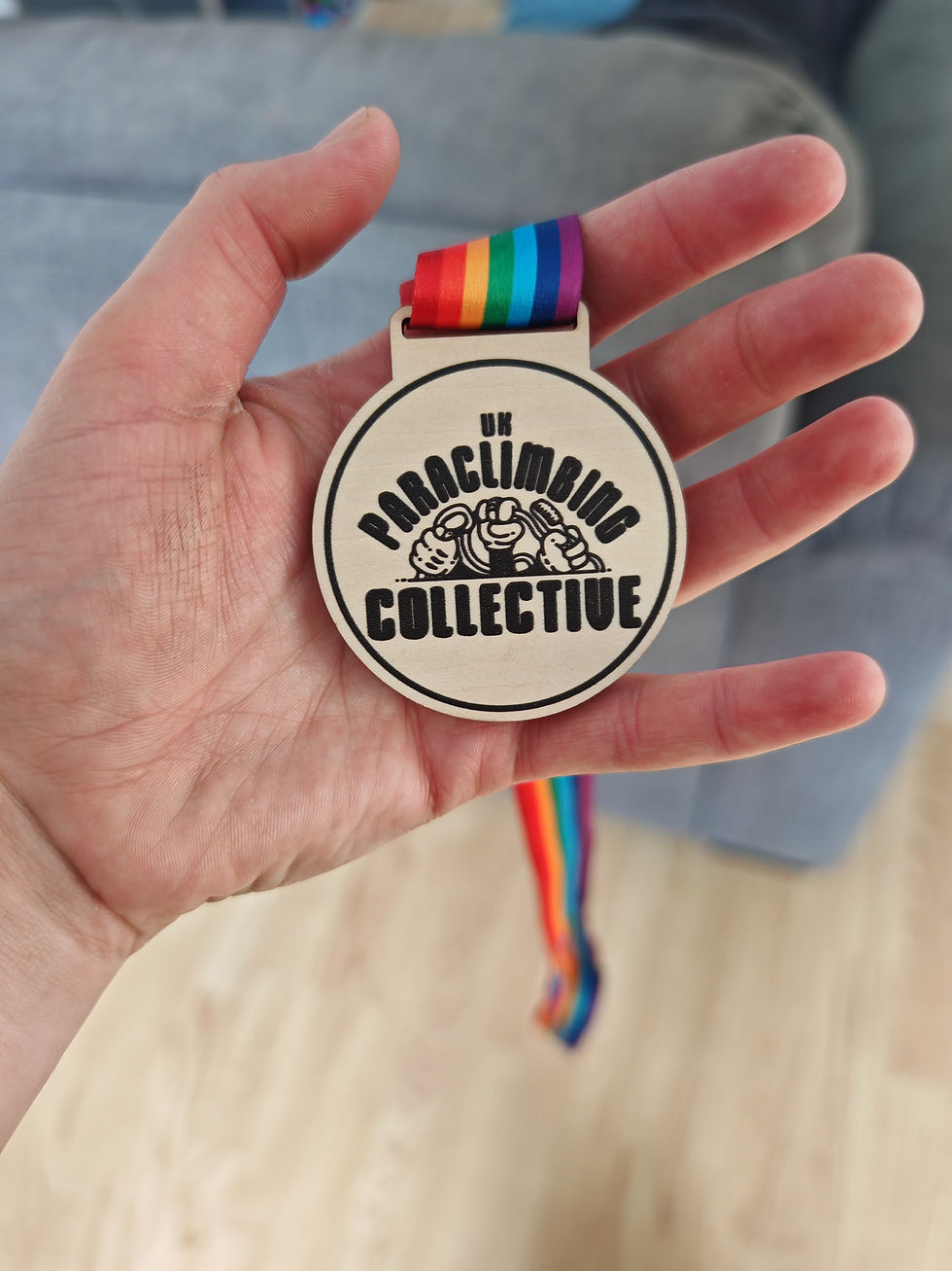 Wooden medeal with UKPC logo and a rainbow ribbon.