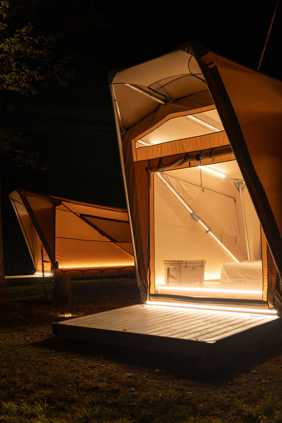A glamping tent lit up during the night time