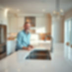 A happy homeowner smiling in a newly renovated kitchen with a large marble island countert