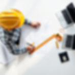 Top-down view of a professional contractor in a safety helmet reviewing architectural blue