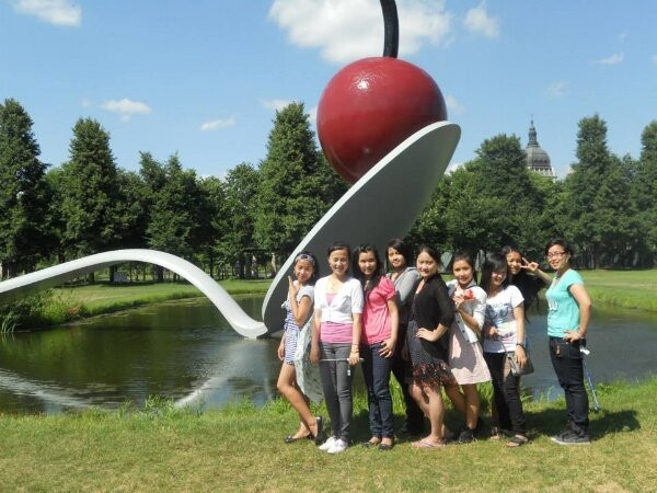 A group of women standing in from of the Cherry Spoon sculpture