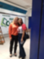 Na foto Rafaela Maciel usando a camiseta com o logo da De Mulher Para o Mundo sorri e abraça a também sorridente Carina Rissi