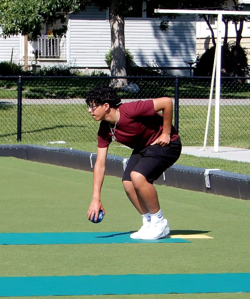 Youth bowling a bowl on a lawn bowling green