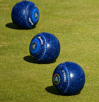 3 blue lawn bowls beside a yellow jack