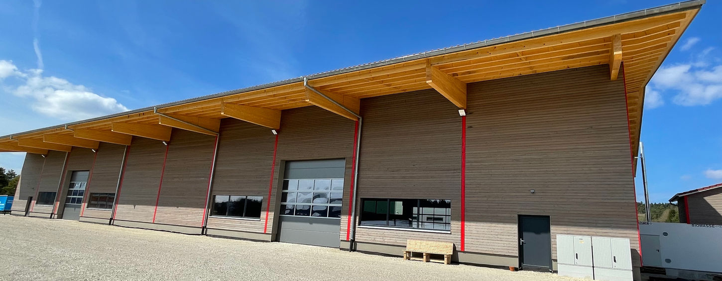 Moderne Lagerhalle mit Holzüberdachung bei blauem Himmel.