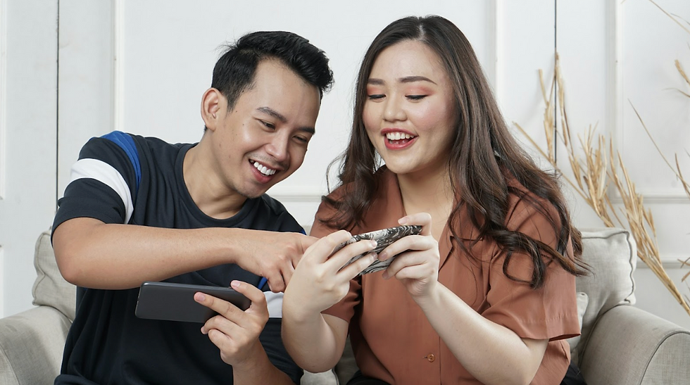 A Asian couple watching and laughing at videos on their smartphones
