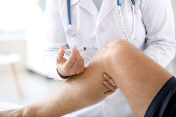 Doctor giving sportsman with joint pain injection in clinic, closeup.jpg