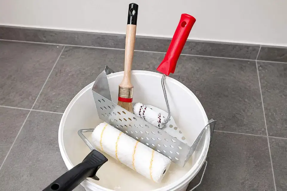 Le Pratiq'Brosse R230G mis en situation dans un seau rond avec pinceau et rouleau de peinture