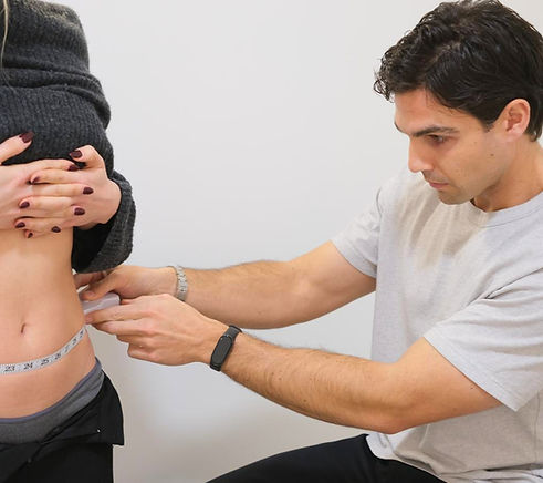 Health professional measuring a patient's waist circumference.