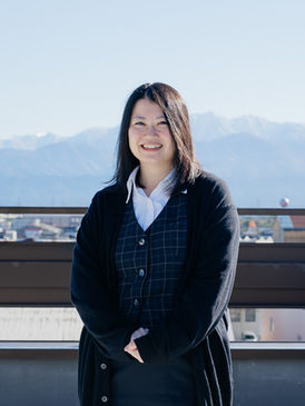 体の前で手を組み、笑顔を浮かべるFさん