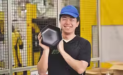 笑顔で製品を持つ製造スタッフのTさん