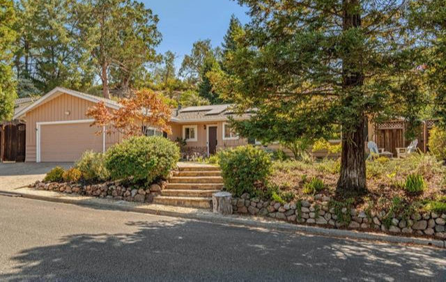 Single-story home in Pleasant Hill California with beige siding, surrounded by greenery, trees, and a stone path. Sunny day with a peaceful suburban vibe.
