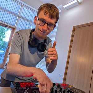 An image of a person showing a thumbsup while on dj decks
