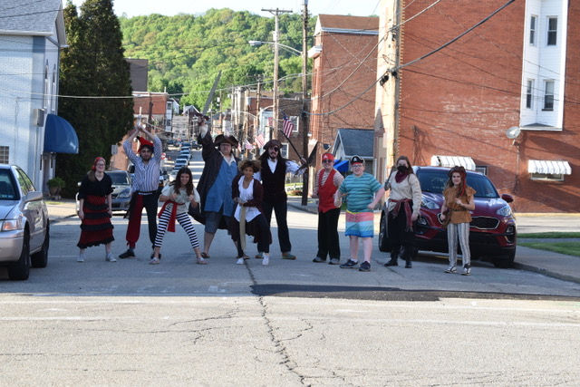 A cast of 10 pirates charge down the main street of Trafford, weapons drawn.
