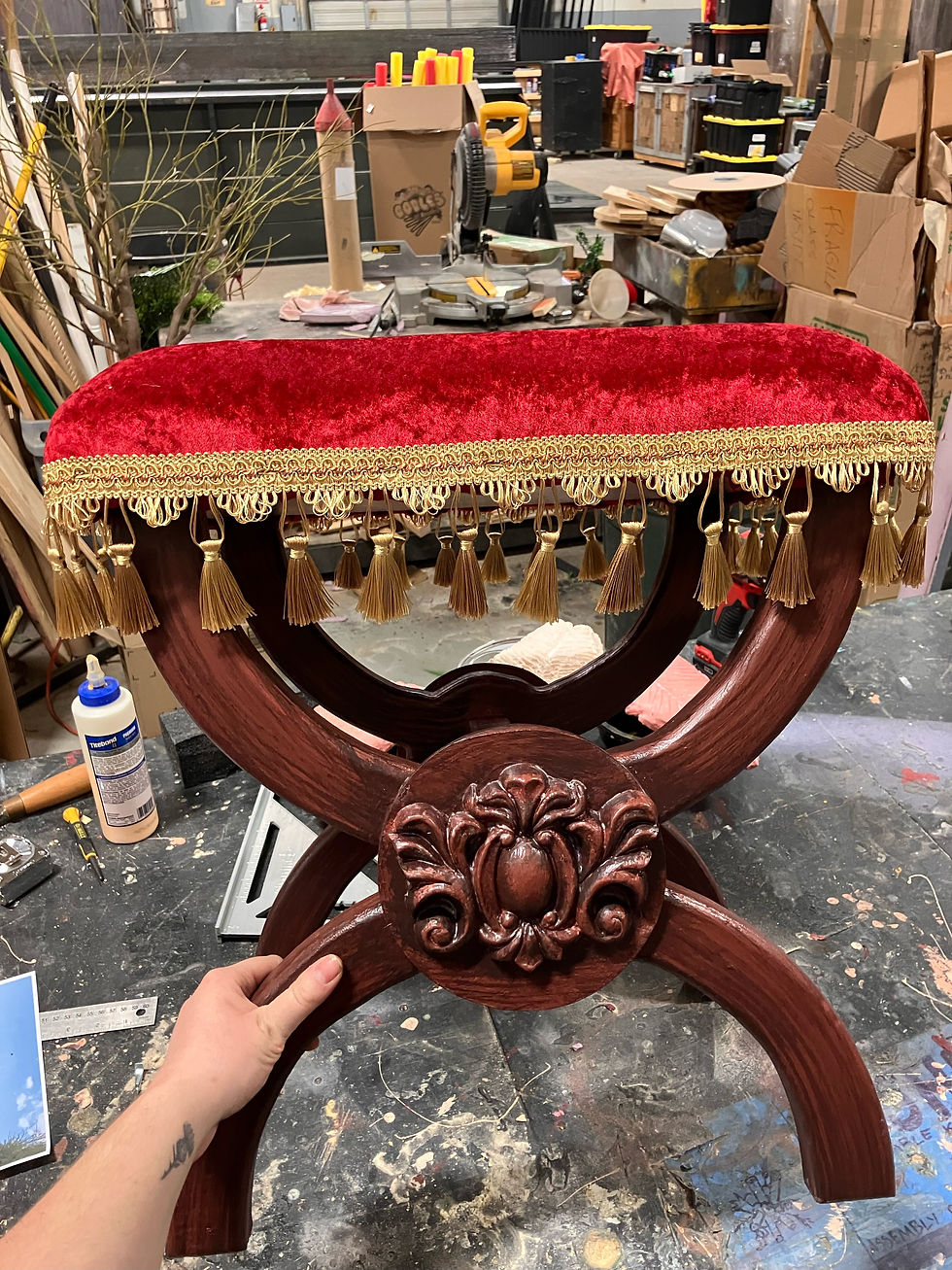 A handmade wood stool with a red velvet upholstered cushion