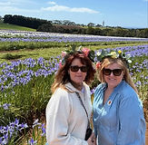 Two women on a tour of a tulip farm smiling in front a field of flowers