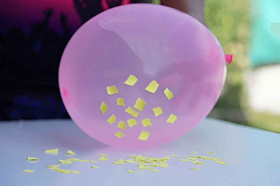 A balloon attracting small paper pieces on a table after being rubbed, demonstrating static electricity in action.