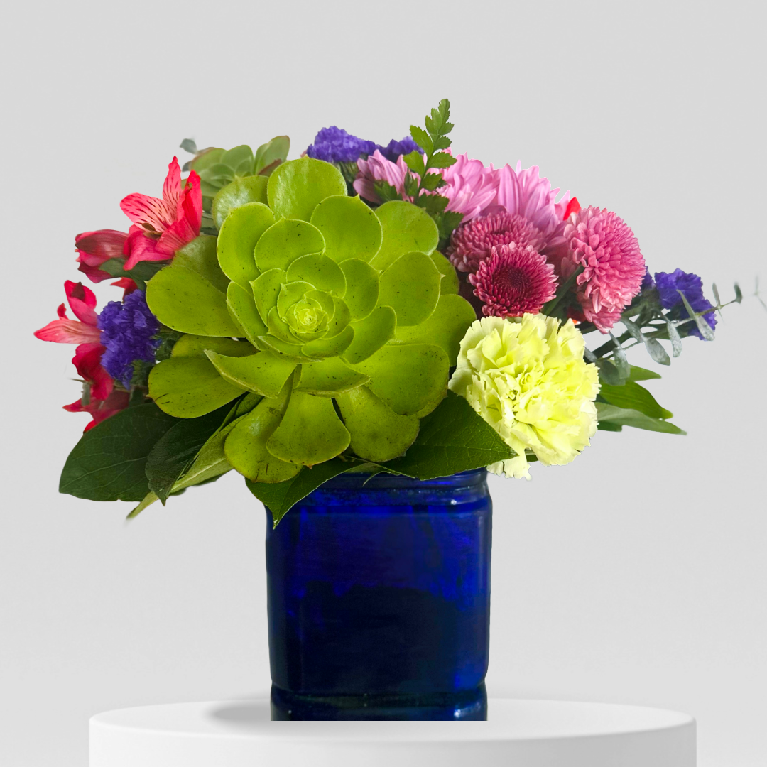 Colorful floral arrangement with vibrant green succulent in a blue vase.