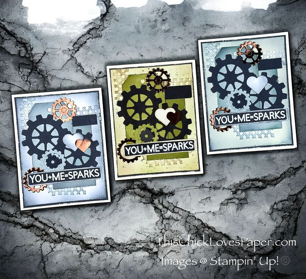 Three handmade cards with gear designs and heart motifs on textured backgrounds. Text reads "YOU + ME = SPARKS." Gray cracked surface.