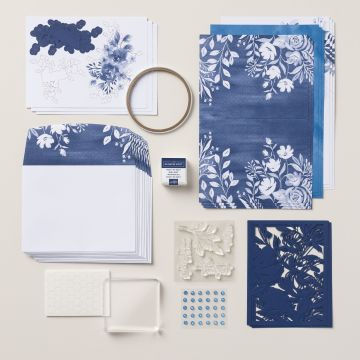 Stampin’ Up!’s Beautiful Blues Kit Collection= Craft supplies are arranged neatly, featuring blue floral patterned paper, envelopes, stamping ink, and embellishments on a light surface.