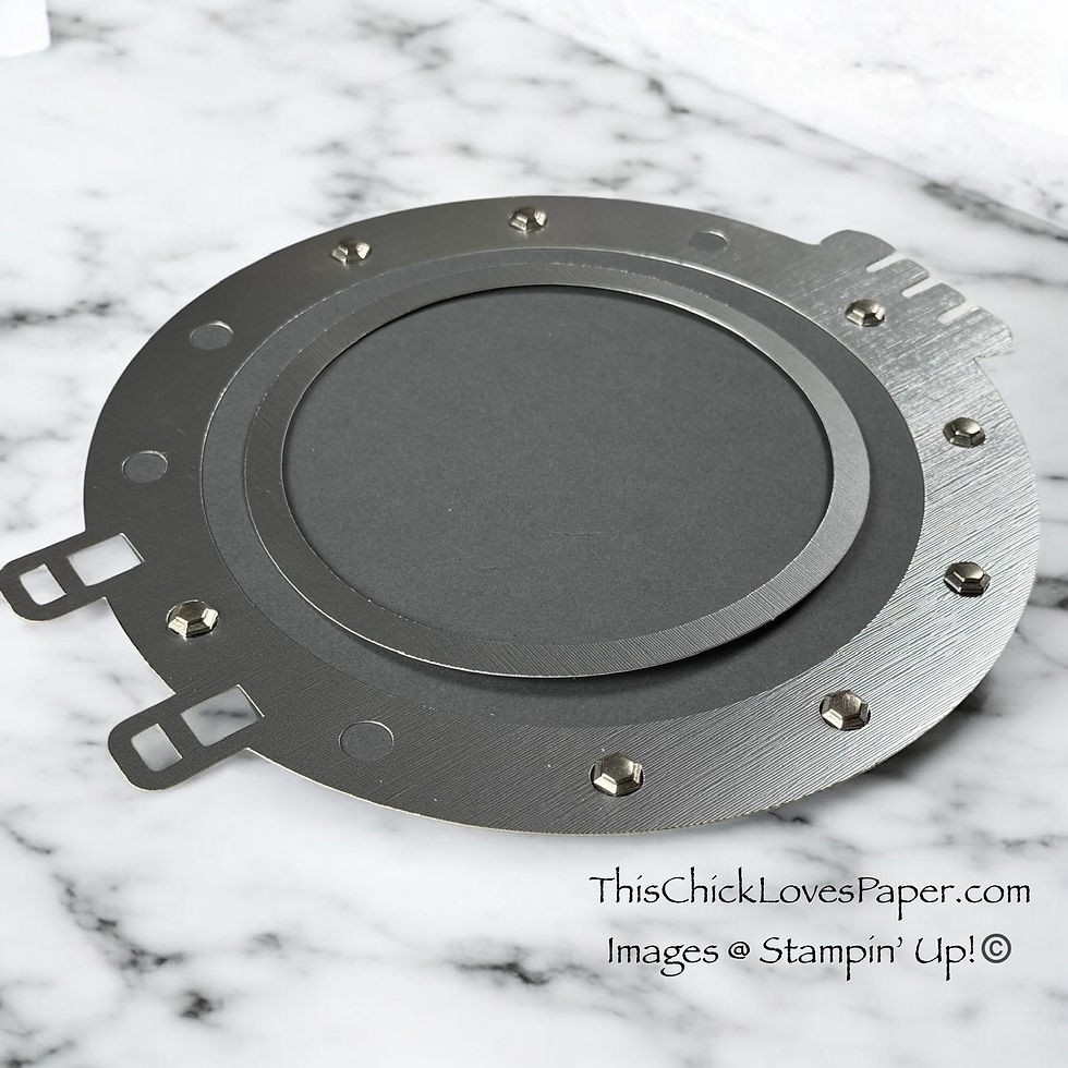 Metallic circular die with bolt details on a marble surface. Text: "ThisChickLovesPaper.com Images © Stampin' Up!"