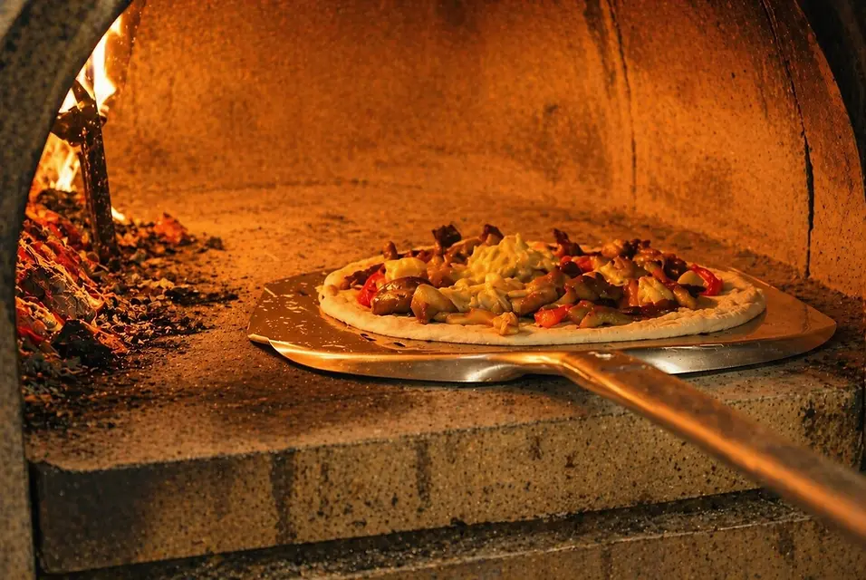 Pizza cotta nel forno a legna con pala nella Pizzeria La Ruota di Evandro a Martinsicuro