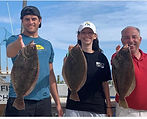 A family posing with fluke they caught in the bay