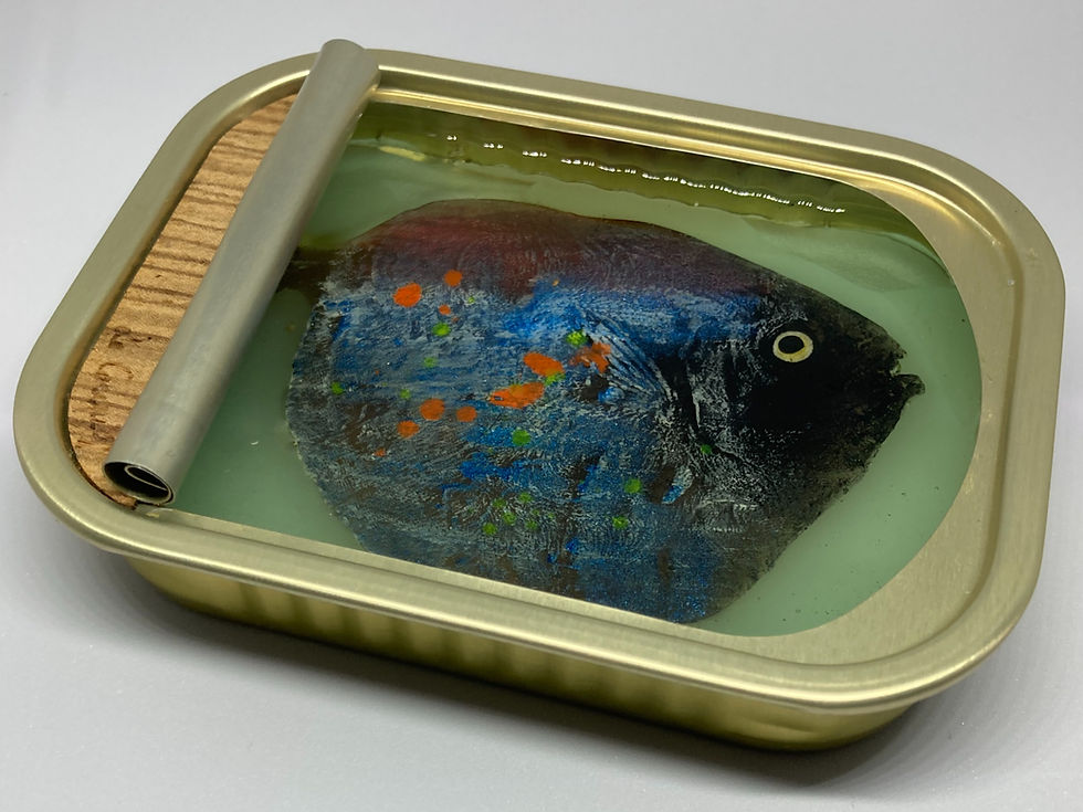 Side view of a mixed-media tin artwork showing a textured blue fish under clear resin by Ortaire de Coupigny.