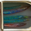 Thumbnail: Mixed media artwork of elongated fish in blue, green, and red tones, displayed in a golden tin can.