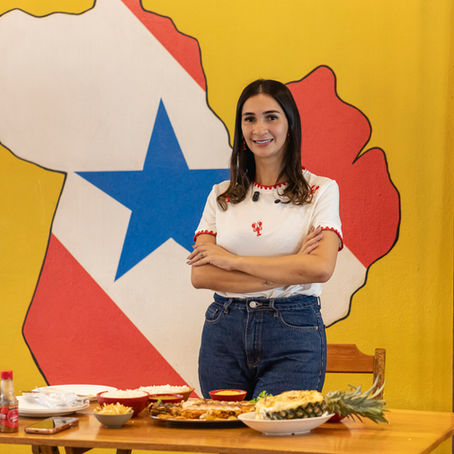 A empresária Tassyane posa com confiança diante da bandeira do Pará em seu restaurante, Sabor Paraense.