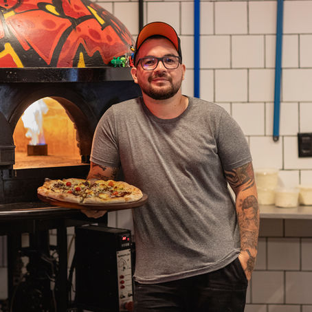 Chef Ângelo segura a pizza "Respeita Januário" diante do forno a lenha na Panizza. Foto: Eduardo Francischelli.