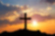 Christian Cross on a hill with clouds and the sun shining through.