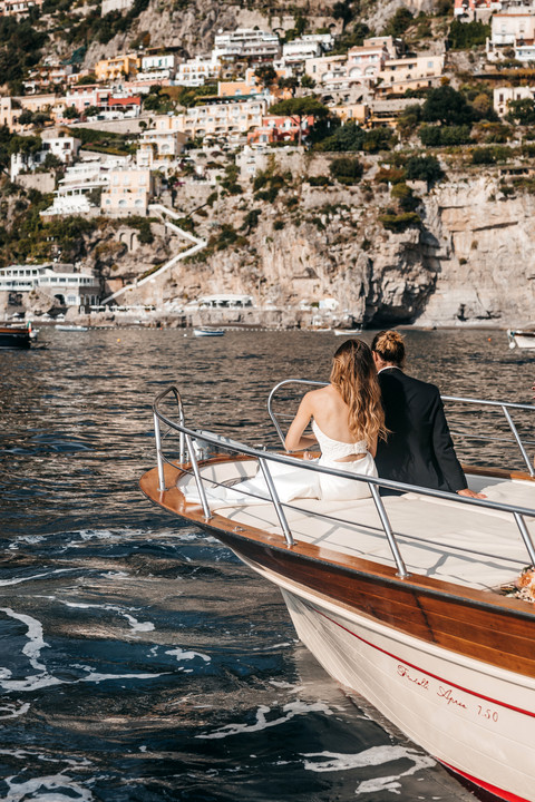 couple sitting on the front of a boat on their wedding day in the Amalfi coast