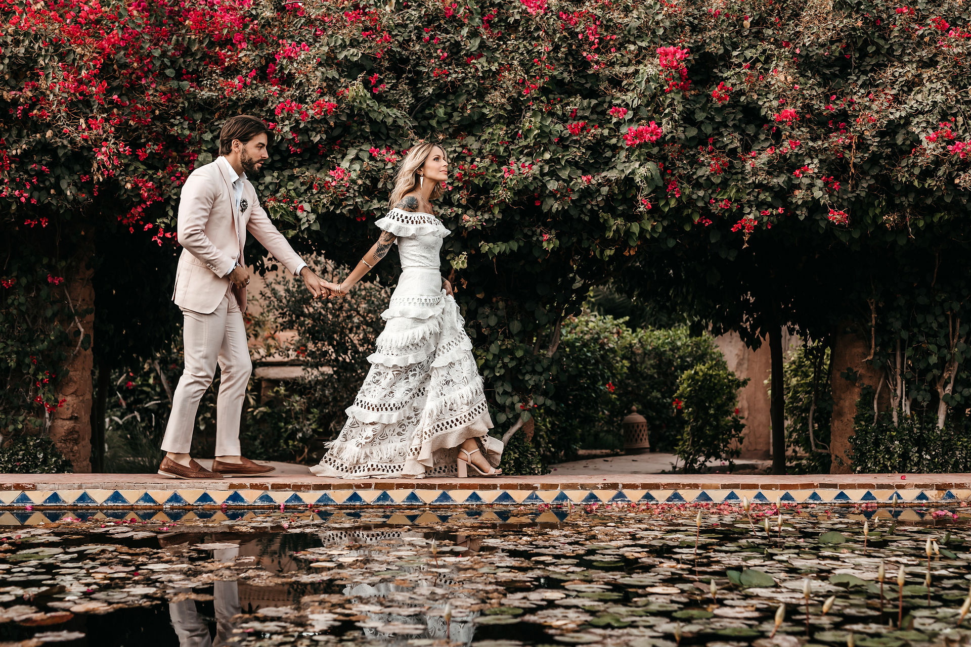 bride and groom walking on the edge of the pond at Beldi Country Club in Marrakesh