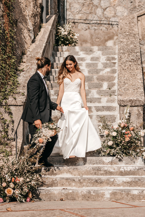bride and groom holding hands walking down steps decorated with flowers on the Amalfi coast