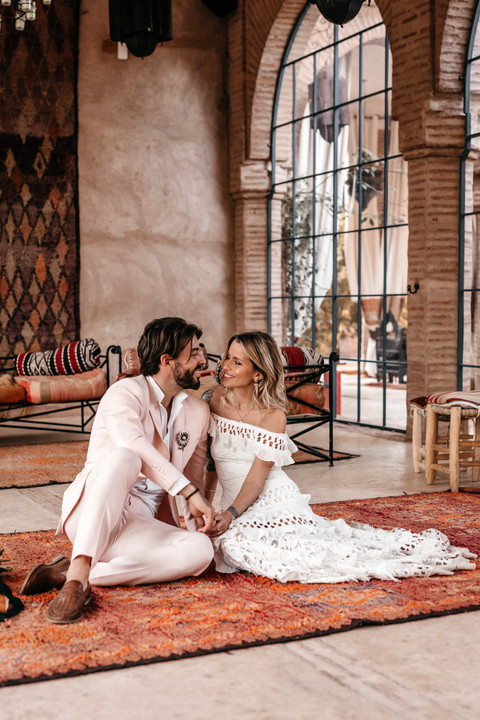 Bride and groom sitting together surrounded by large moroccan rugs at Beldi Country Club for their intimate destination elopement wedding day in Marrakesh