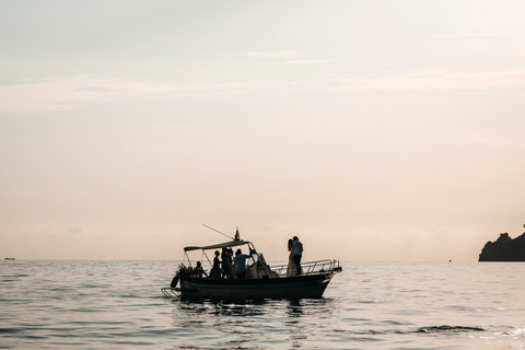 bride and groom standing on the front of a boat at golden hour in the Amalfi coast
