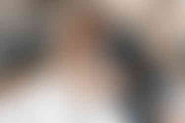 bride and groom sitting on the front of a boat with the houses and mountain side of Positano in the background on their elopement day in the Amalfi Coast