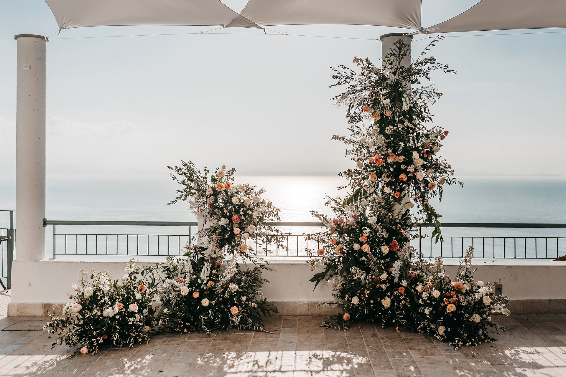 Floral ceremony installation by the florist Sass flower. Two pillars of peachy roses on the terrace overlooking the sea for an elopement ceremony spot 