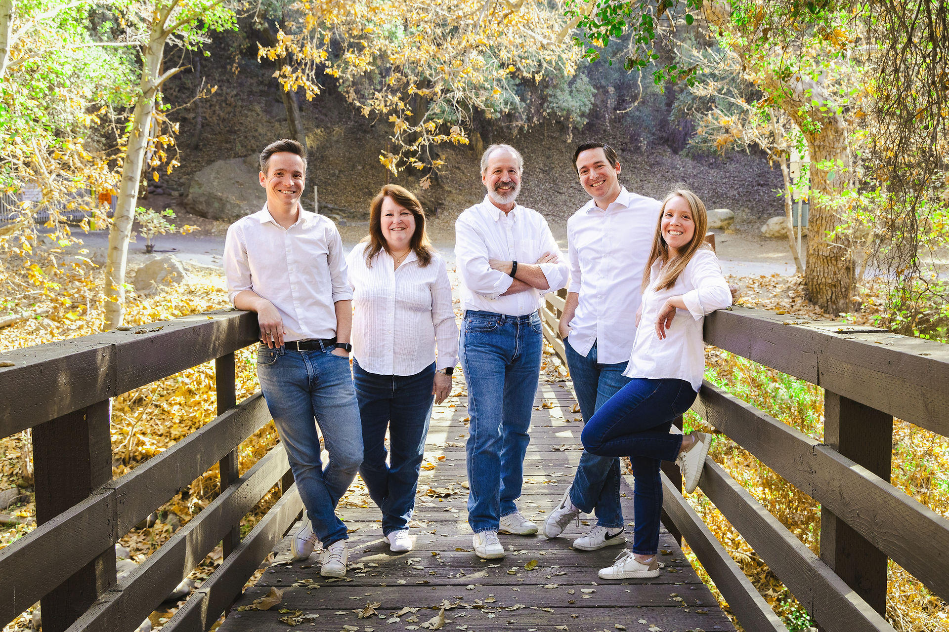 family wearing matching outfits of white shirts and jeans pose on a bridge