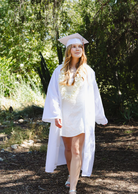 candid of graduate walking in white gown