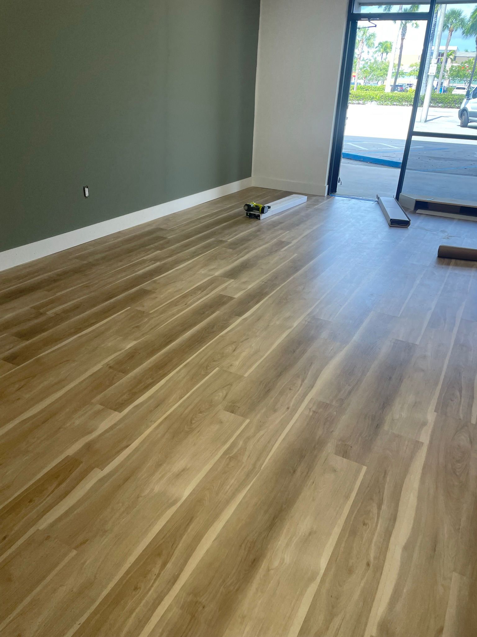 Wood-look plank flooring installed in a commercial space with a glass storefront entrance