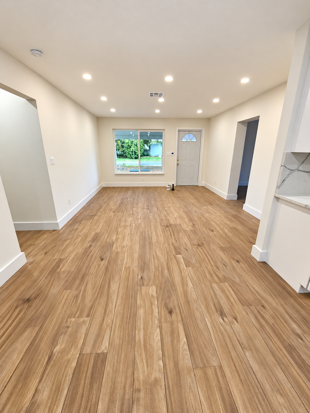 Renovated room with warm wood-look plank flooring and white walls