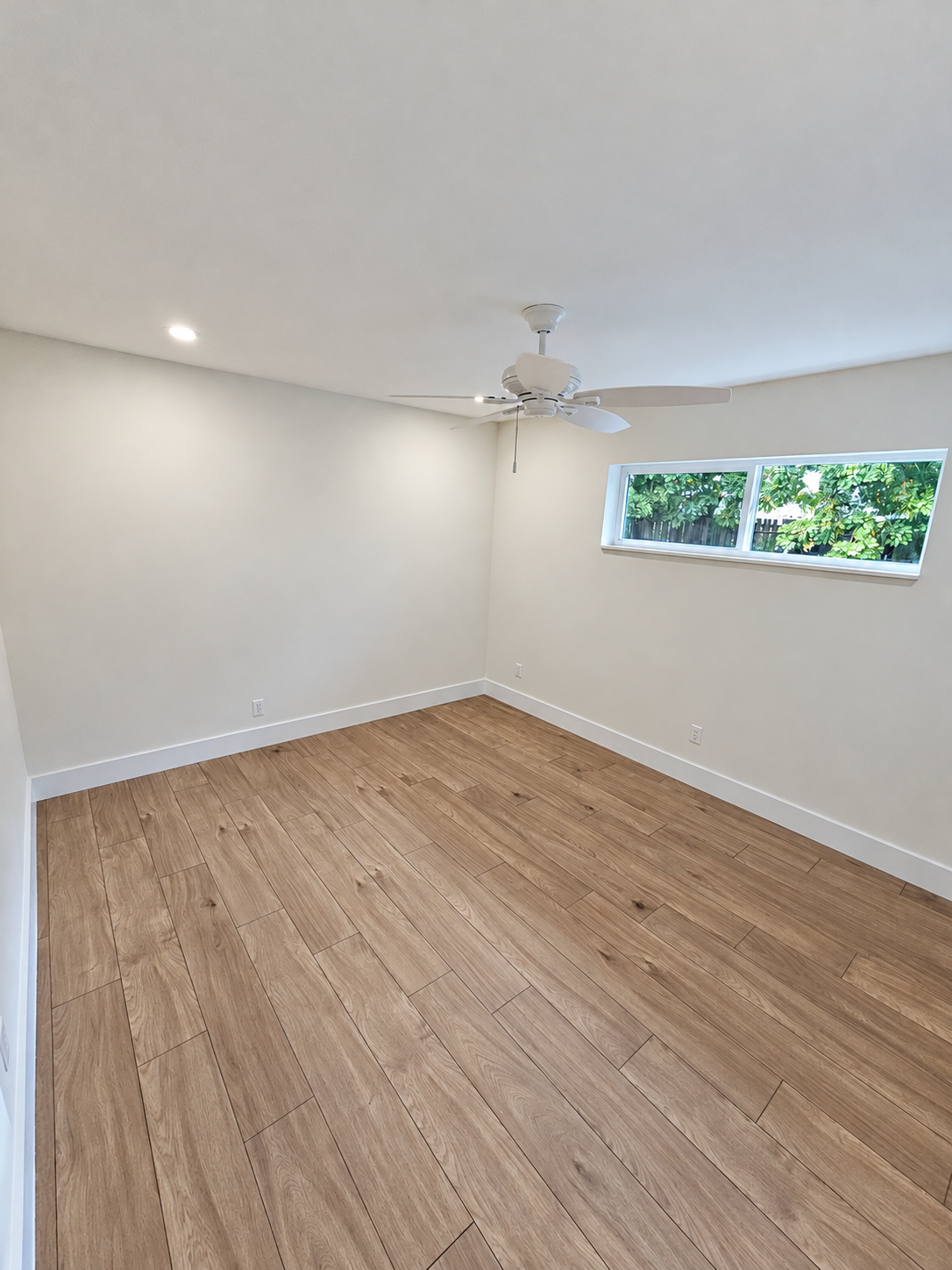 Remodeled room with wood-look flooring, white walls, and a ceiling fan