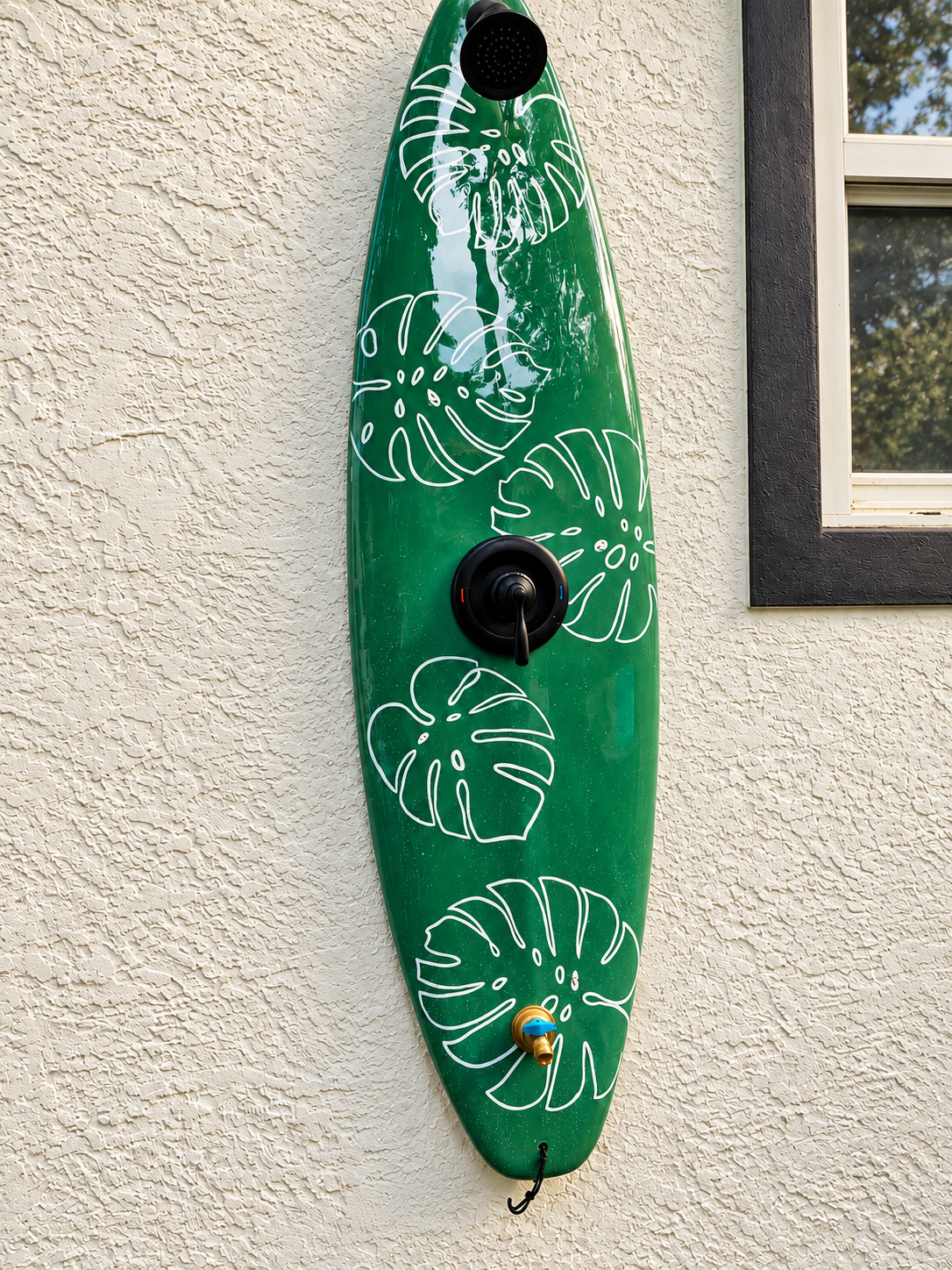 Custom green surfboard outdoor shower with white leaf designs and black fixtures