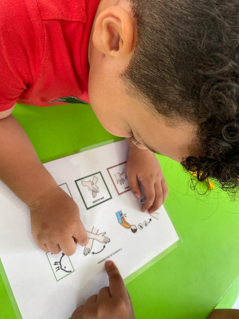 Niño pequeño señalando imágenes en una hoja de papel; Personitas Brillante
