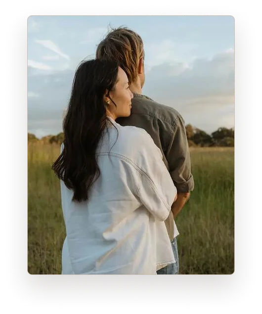 A couple standing close together in a quiet field