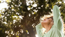 Woman smiling and looking towards the sun, embodying a sense of wellbeing
