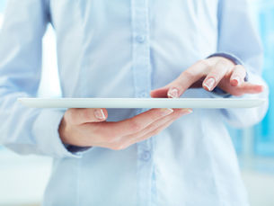 Close-up of a woman's hands with a French manicure using a white digital tablet.